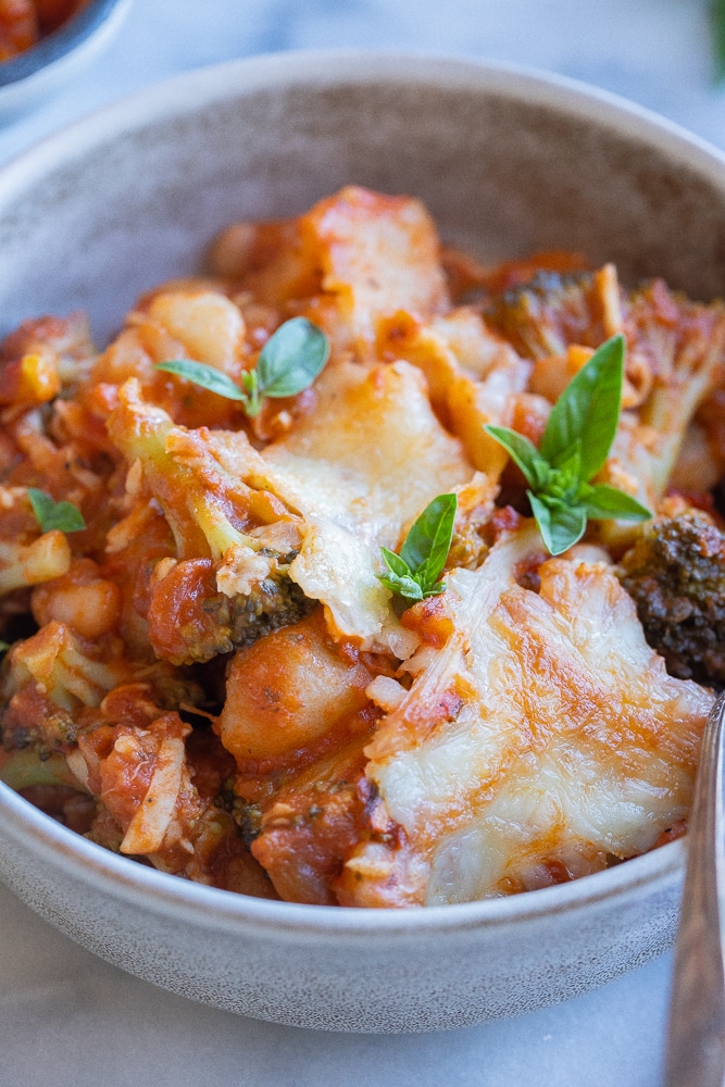 close up of this protein packed vegetarian gnocchi broccoli white bean bake in a dinner bowl with a fork