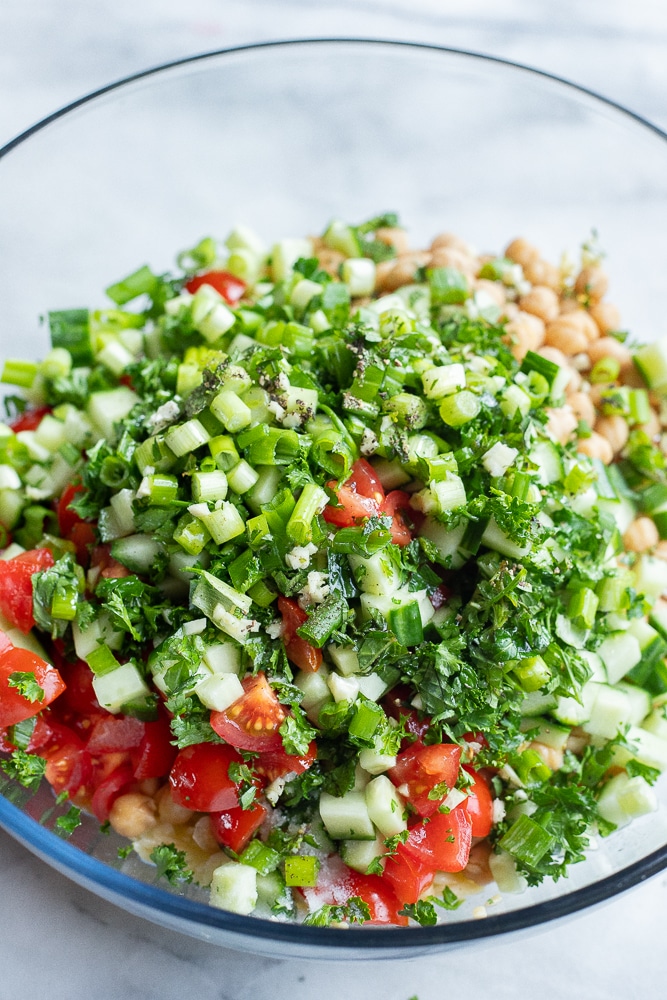 showing how to make this summery tabouli salad with all the ingredients in a large mixing bowl