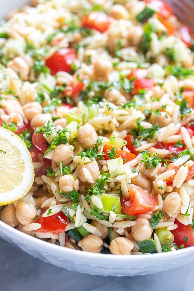 tabouli inspired orzo salad with chickpeas in a large serving bowl with a lemon wedge