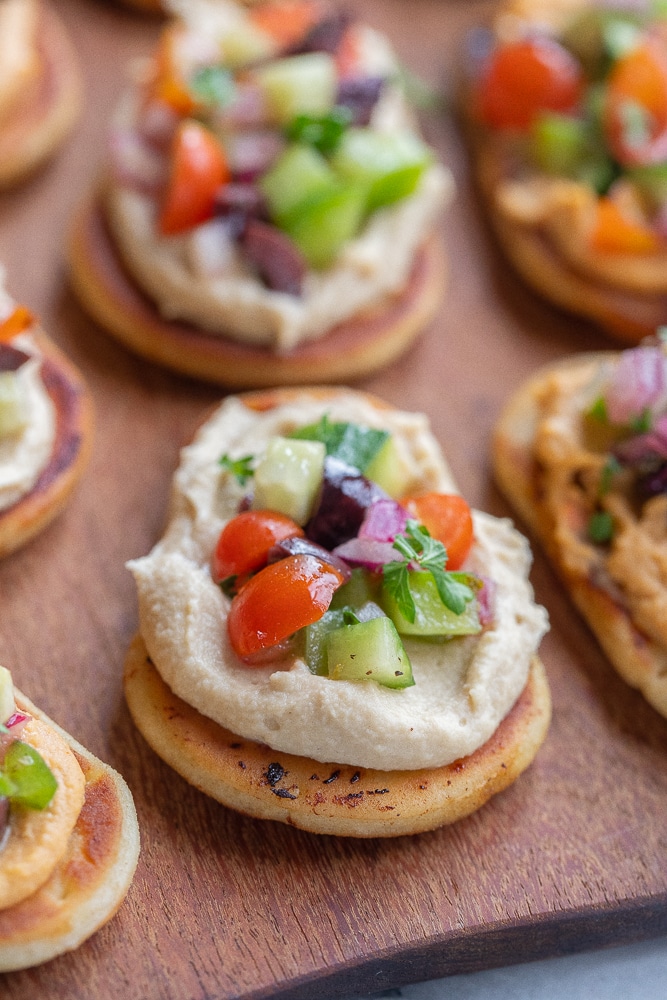 Close up of a Greek Salad Naan Bread with hummus on a cutting board