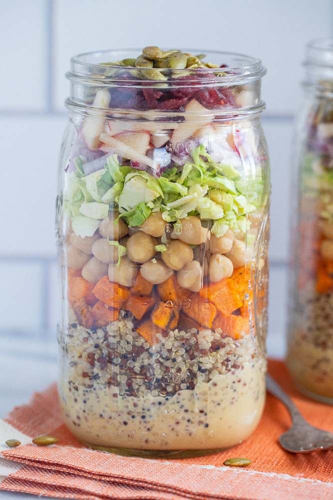 fall inspired mason jar salad on an orange napkin with a fork