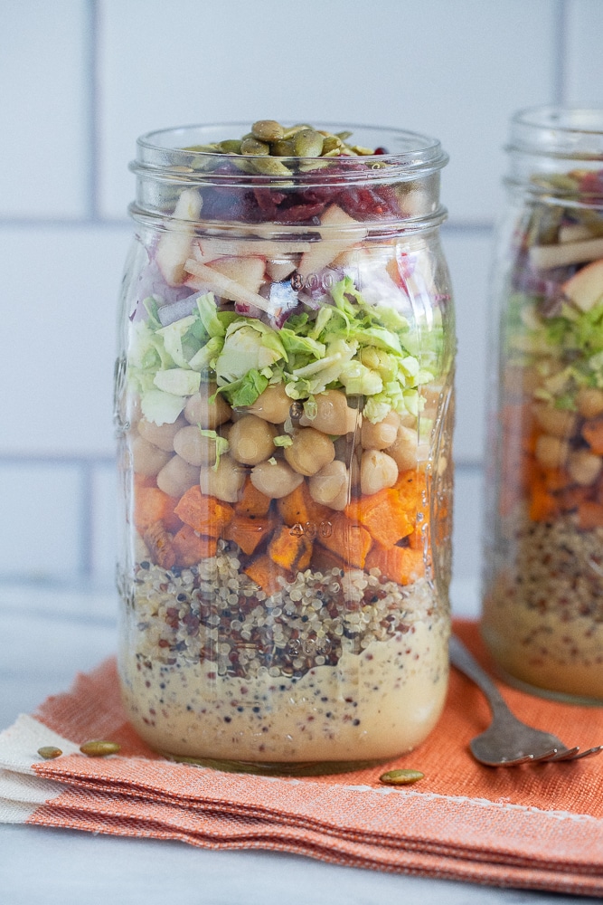 fall harvest salad in a mason jar on an orange napkin with a fork