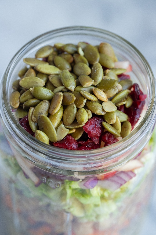 close up of the pepitas and dried cranberries on top of the mason jar fall salads