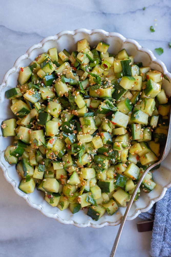 chili garlic cucumber salad in a serving bowl with a spoon