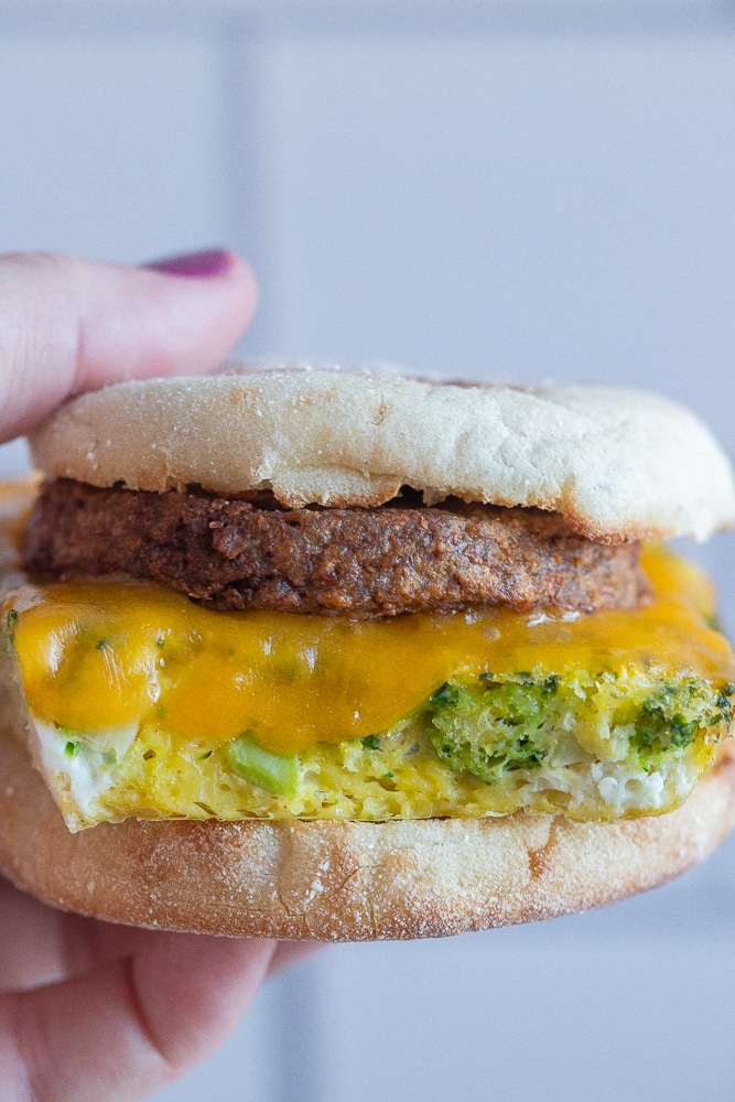 a hand holding a meal prep vegetarian breakfast sandwich