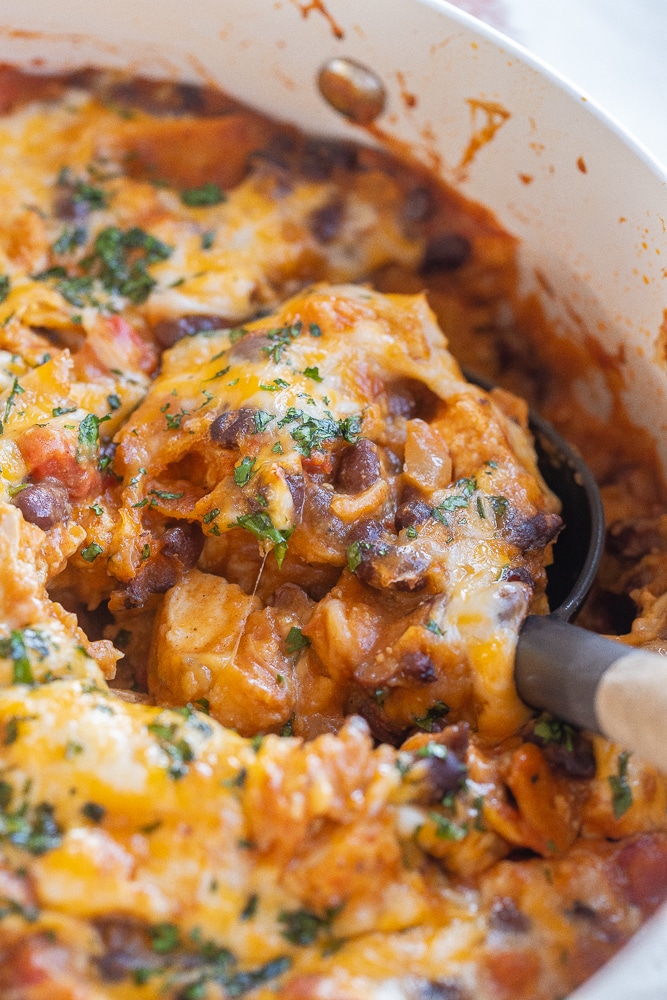 A serving spoon scooping up some of the tofu enchilada skillet