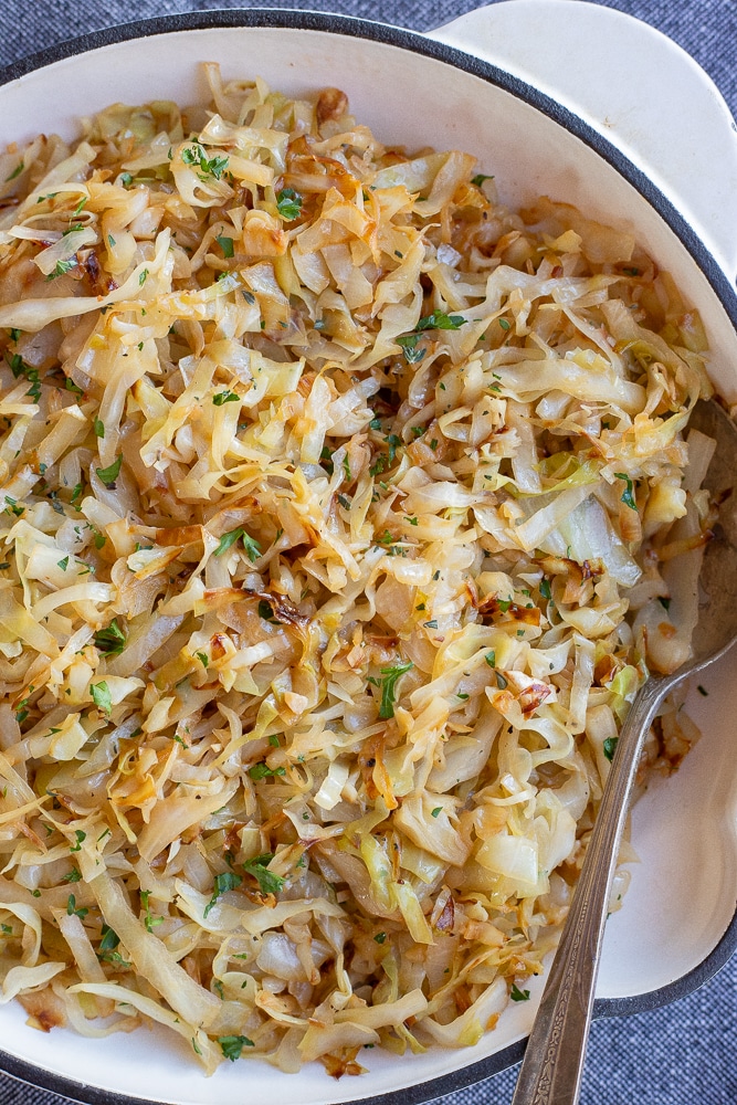 frying pan with sauteed cabbage and a spoon