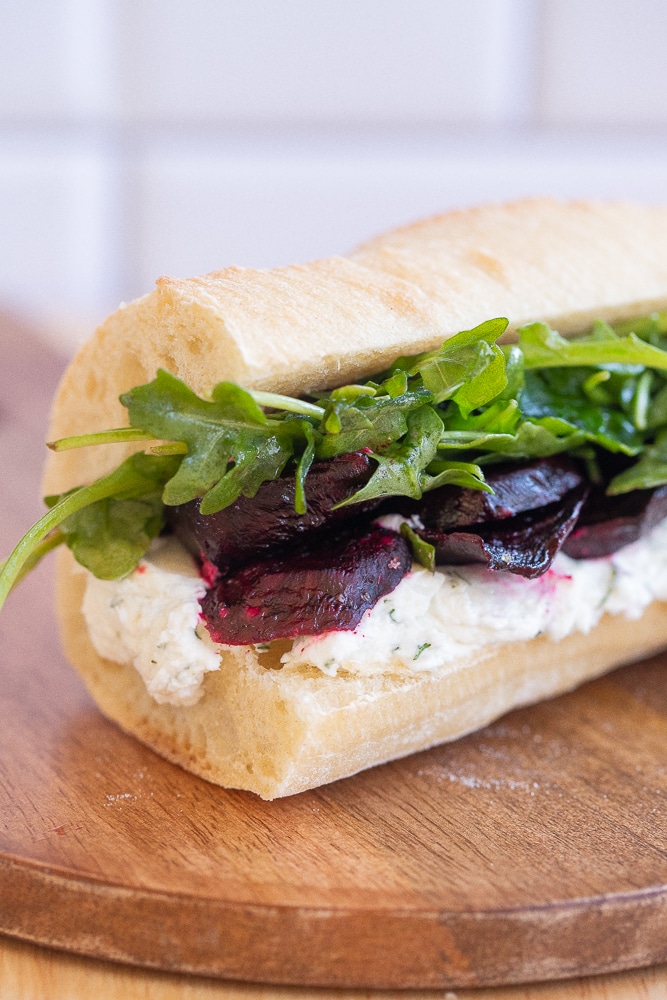 close up of a roasted beet sandwich with horseradish goat cheese and arugula