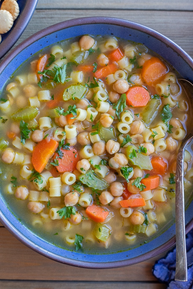 vegetarian chickpea noodle soup in a bowl with a soup spoon