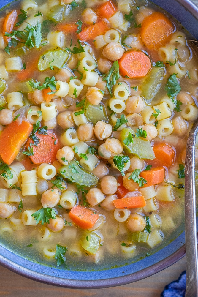 close up of a bowl of vegan chickpea noodle soup with vegetables